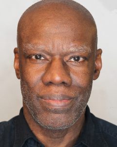Older, bald, African American man and stubble on his chin. 
